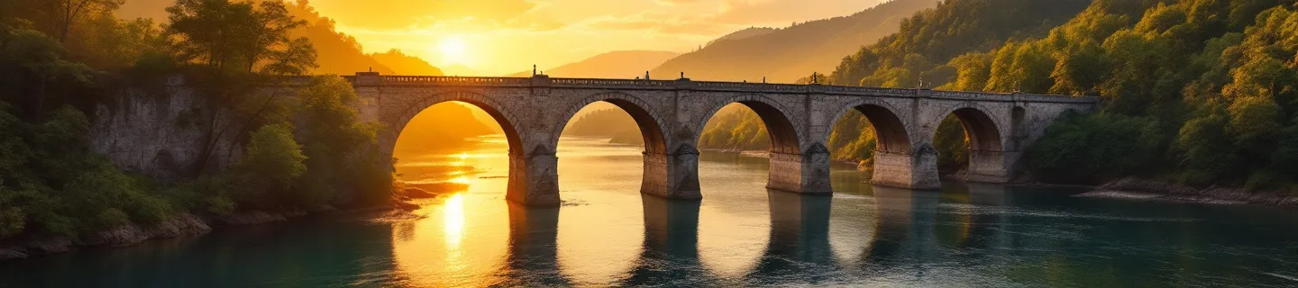 Stone bridge with multiple arches spanning a wide river at golden hour