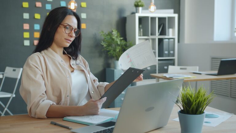 Owner reviewing documents and a laptop at a desk.