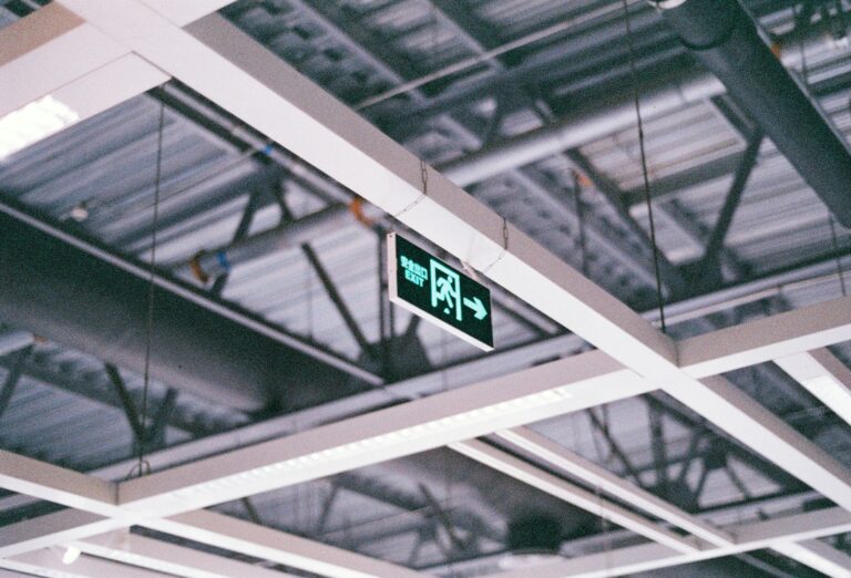 Green illuminated exit sign on a commercial ceiling.