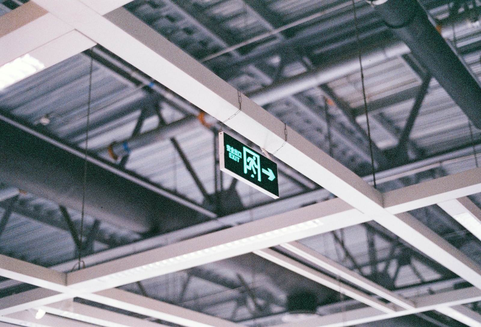 Green illuminated exit sign on a commercial ceiling.