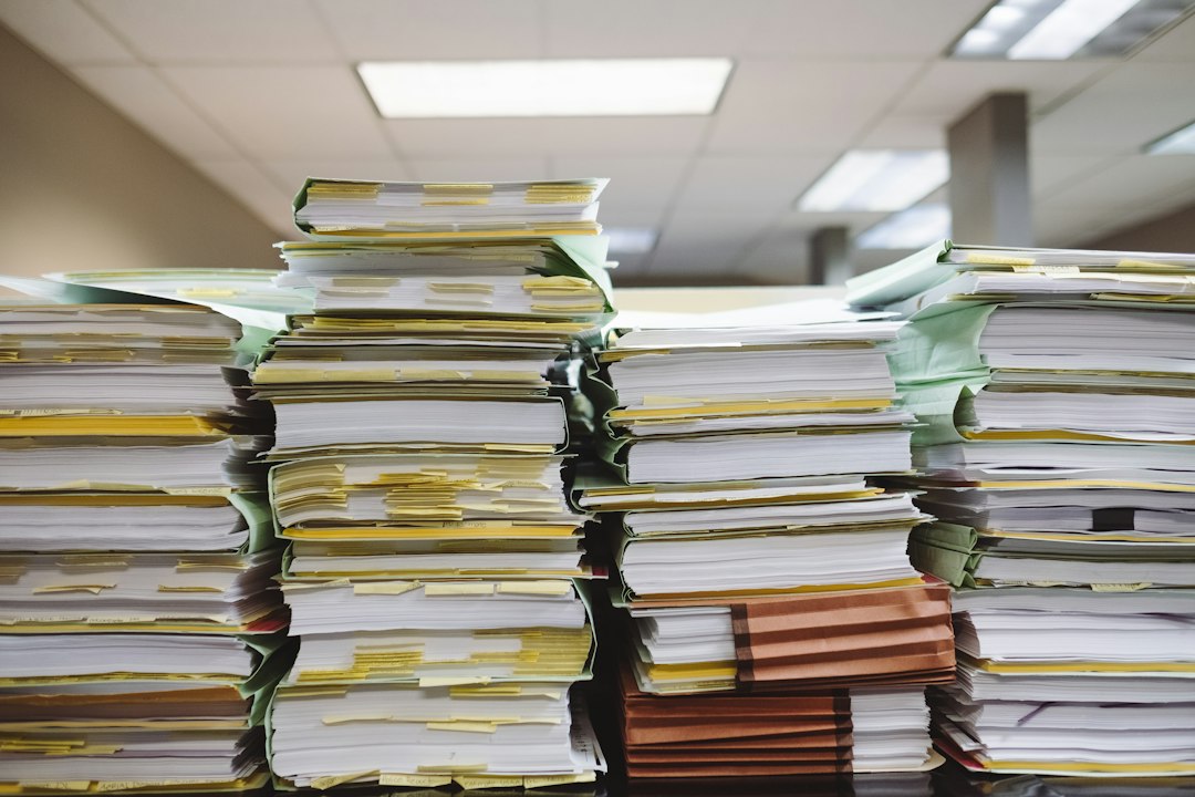 Stacks of labeled paper documents and file folders on a desk